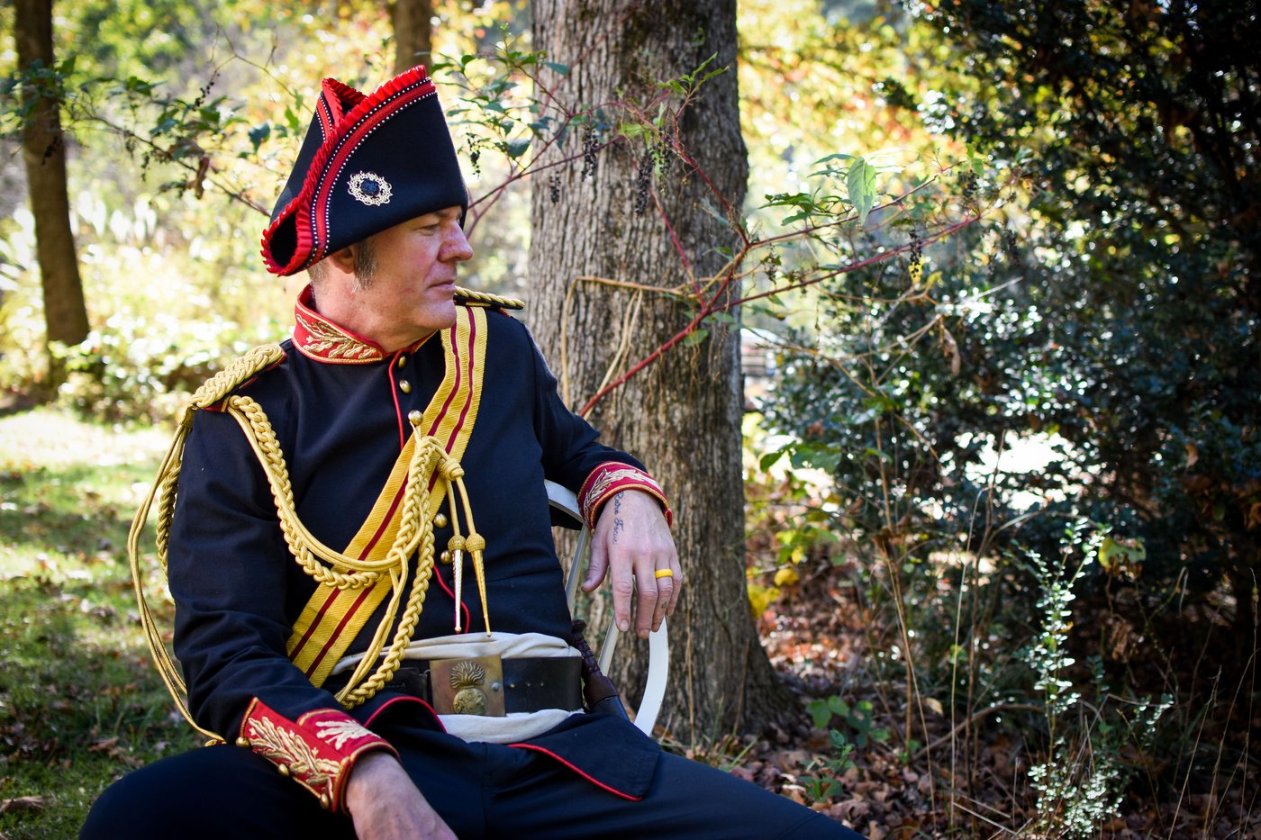 Carl Lee Tolbert in a Napoleonic-era dress uniform, seated against a tree in autumn woodland, from the 2022 Bourguise Christmas in Canton card.